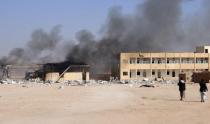 Houthi fighters walk as smoke rises from a military supply post after it was hit by an air strike in Yemen's northwestern city of Saada April 1, 2015. REUTERS/Naiyf Rahma