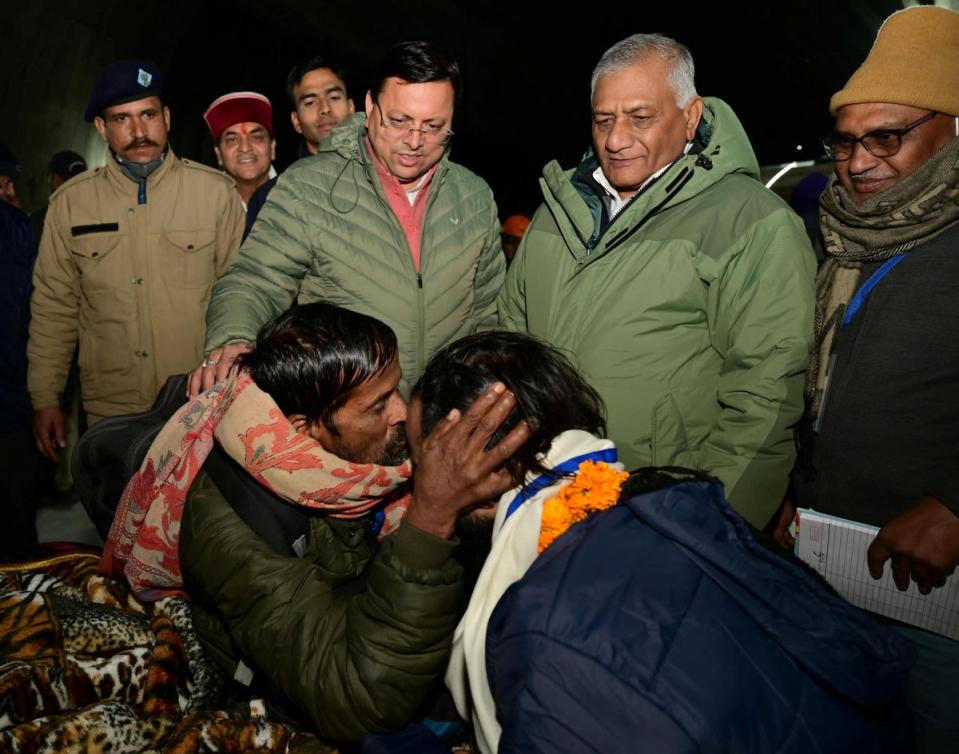 A man kisses a rescued worker after being rescued from the collapsed tunnel site as Pushkar Singh Dhami, Chief Minister of the northern state of Uttarakhand (via REUTERS)