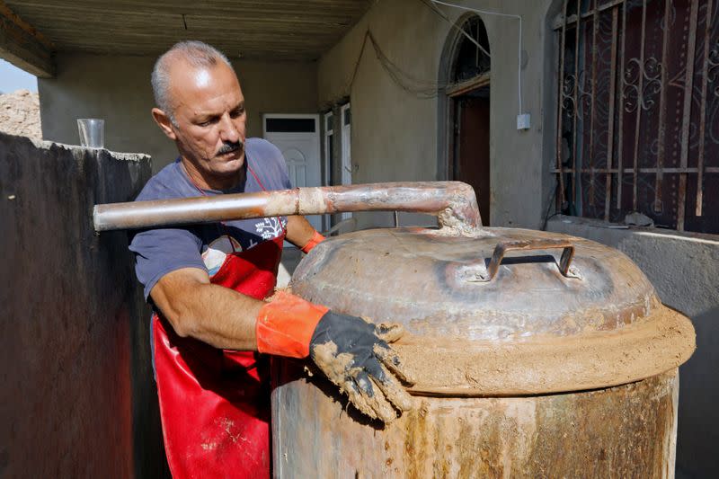 Saad Hussein, an Iraqi Yazidi, puts the clay in the process of producing Arak liquor out of dates, on the outskirts of Mosul