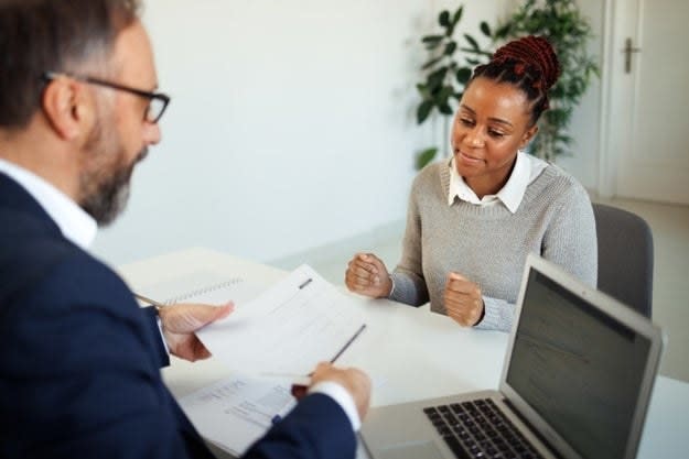 A woman shows her resume to a hiring manager during a job interview