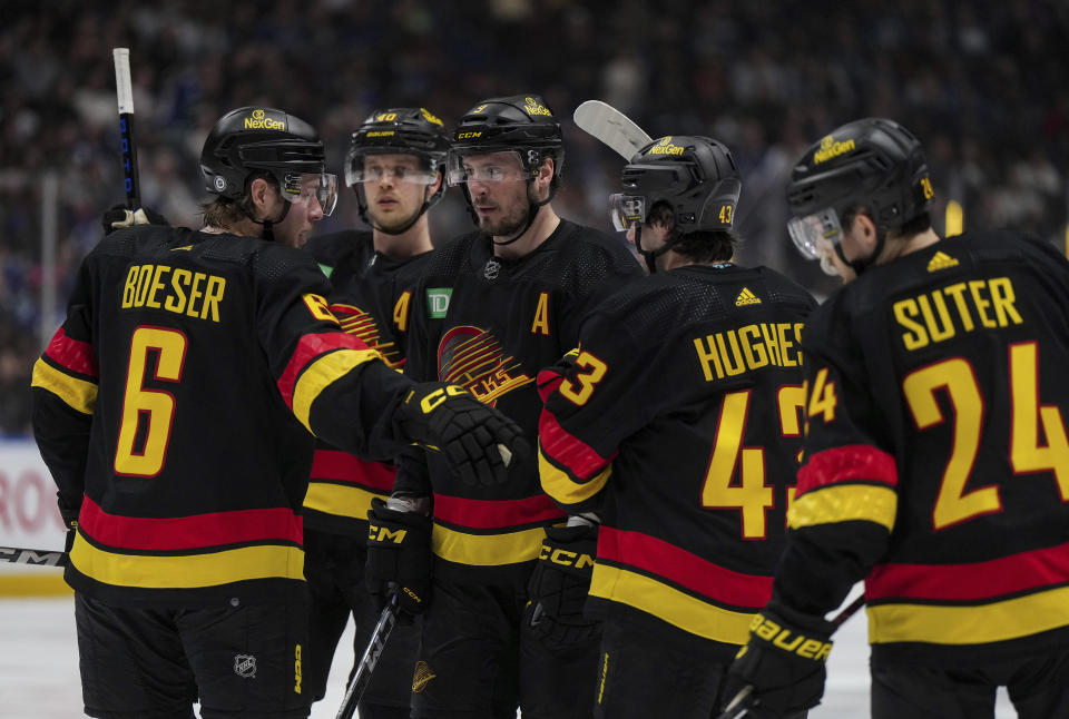 Vancouver Canucks' Brock Boeser (6) talks to J.T. Miller, center, as Elias Pettersson, back left, Quinn Hughes (43) and Pius Suter (24) listen before a power play against the Columbus Blue Jackets during the third period of an NHL hockey game Saturday, Jan. 27, 2024, in Vancouver, British Columbia. (Darryl Dyck/The Canadian Press via AP)