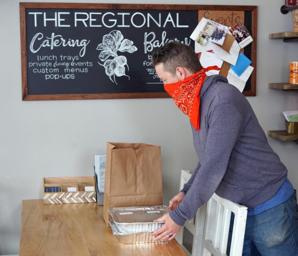 Kevin Grossi, the owner of the Fort Collins, Colorado-based restaurant The Regional, stacks to-go orders on a table ready for pickup during the coronavirus outbreak. Grossi is struggling to keep his 18-month-old restaurant running during the widespread closure orders.