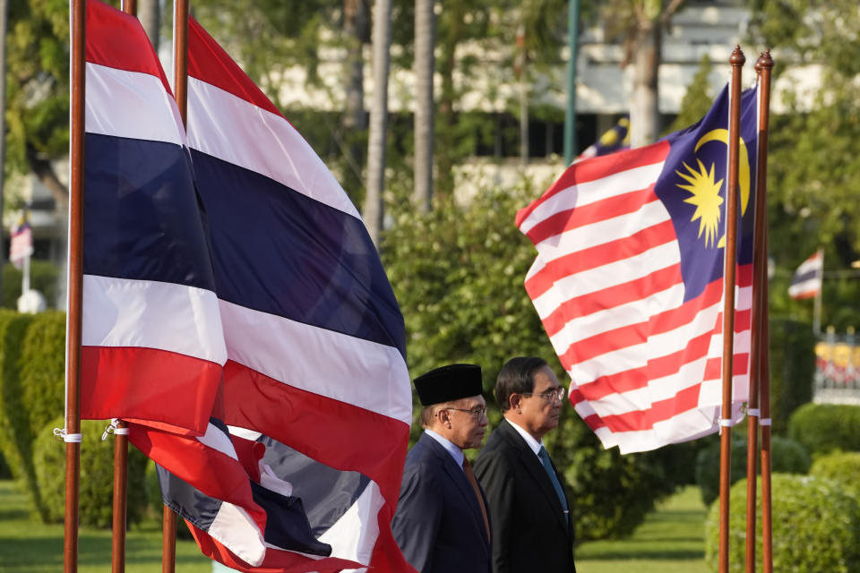 Malaysia's Prime Minister Anwar Ibrahim, left, and Thailand's Prime Minister Prayuth Chan-ocha listen to their national anthems during a welcoming ceremony at the Government House in Bangkok, Thailand, Thursday, Feb. 9, 2023. (AP Photo/Sakchai Lalit)