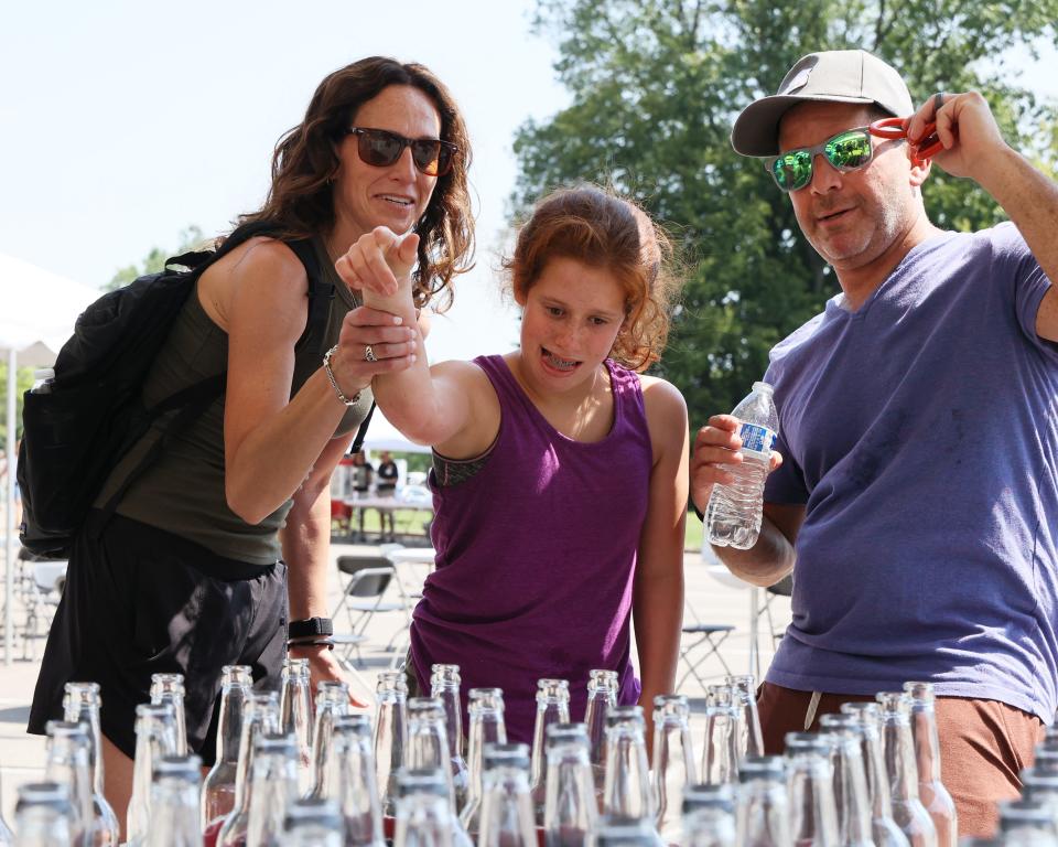 Jodie and Josh Jacobs cheer on their daughter, Allie, as she plays a game of ring toss at JARC's carnival in 2023.