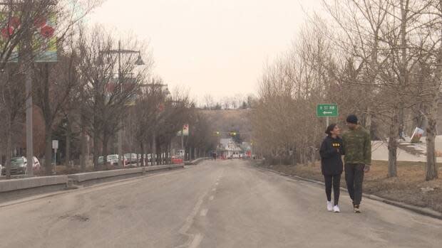 A couple strolls down a portion of Calgary's Memorial Drive last March, a popular spot for walkers and joggers along the Bow River, which was closed to traffic to give people space to physically distance themselves.  (Helen Pike/CBC - image credit)