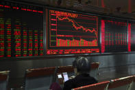 A Chinese woman monitors stock prices at a brokerage in Beijing, Friday, Oct. 19, 2018. Asian stock markets sank Friday after Wall Street declined on losses for tech and industrial stocks and Chinese economic growth slowed. (AP Photo/Ng Han Guan)