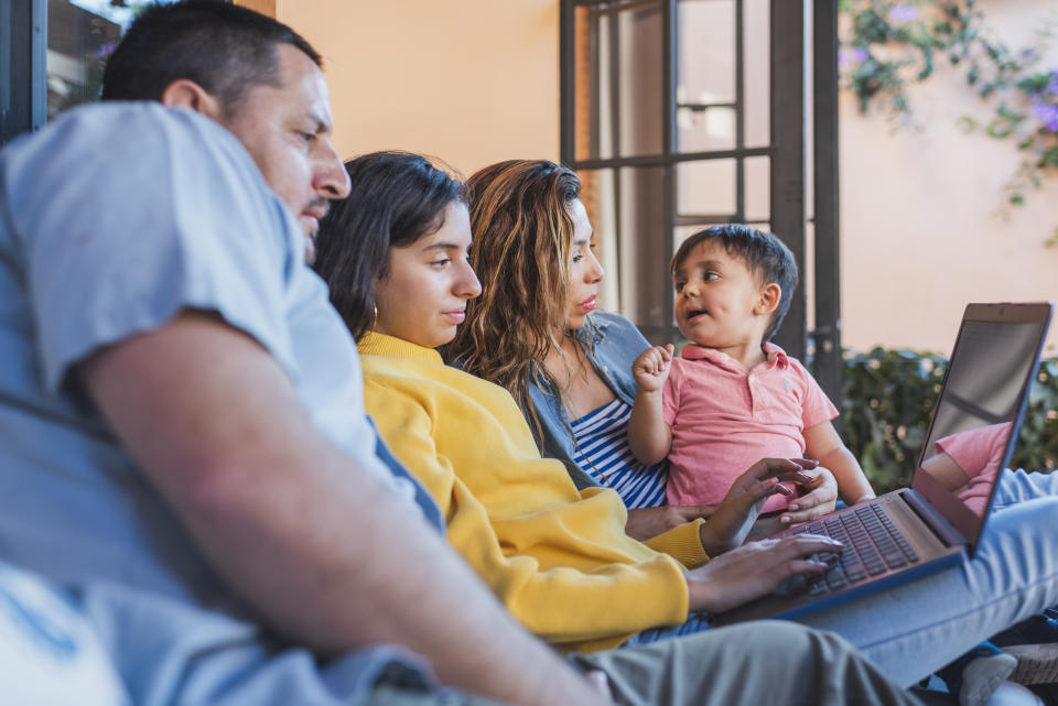 Family using laptop on outdoor porch