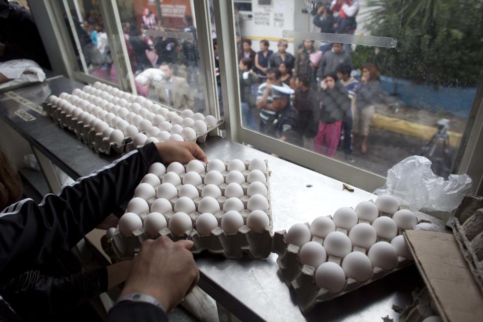 A city worker sells eggs at government subsidized prices as people line up outside the city truck in Mexico City, Friday, Aug. 24, 2012. The Mexican government is battling an egg shortage and hoarding that have caused prices to spike in a country with the highest per-capita egg consumption on earth. About 11 million chickens were slaughtered after a June outbreak of bird flu. (AP Photo/Alexandre Meneghini)