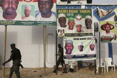 Policemen walk in front of posters of candidates of Nigeria's President Goodluck Jonathan People's Democratic Party in Kano, March 26, 2015. REUTERS/Goran Tomasevic