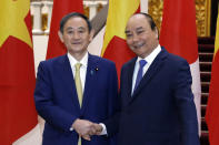 Japanese Prime Minister Yoshihide Suga, left, and his Vietnamese counterpart Nguyen Xuan Phuc shake hands at the Government Office in Hanoi, Vietnam Monday, Oct. 19, 2020. (Luong Thai Linh/Pool Photo via AP)