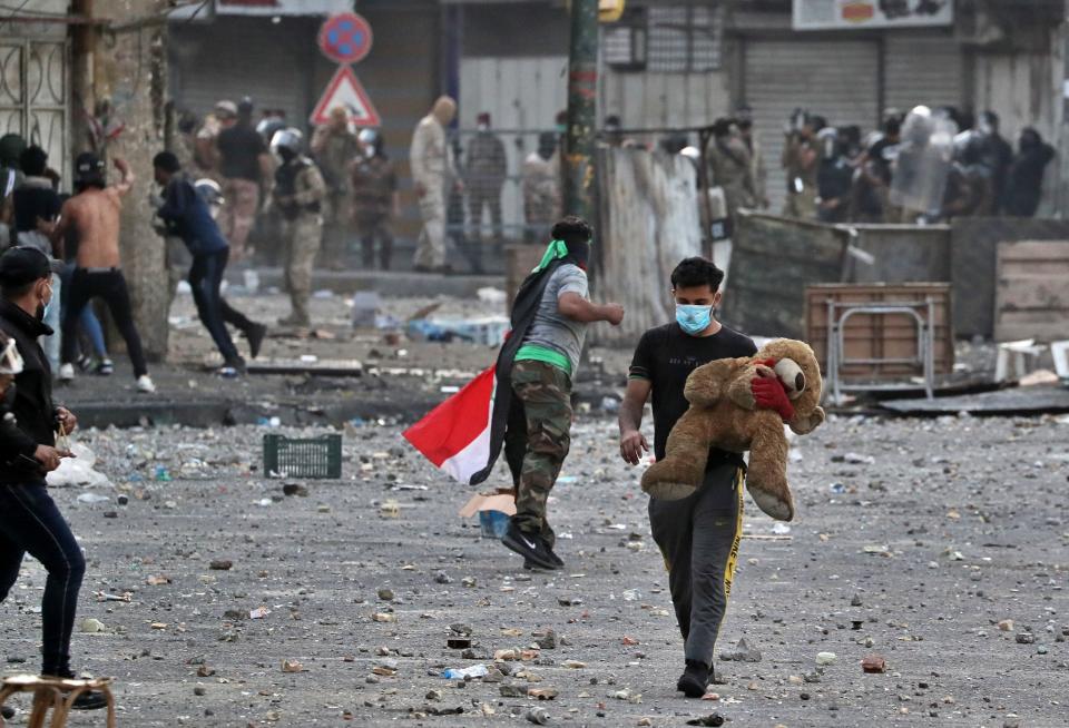 A protester holds his Teddy Bear during clashes between Iraqi security forces and anti-government demonstrators, at Khilani Square in Baghdad, Iraq, Friday, Nov. 15, 2019. (AP Photo/Khalid Mohammed)