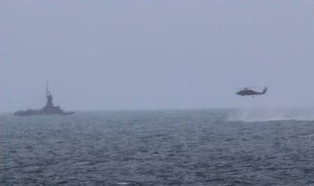 An MH-60R helicopter, attached to the USS Sampson (DDG 102), approaches an Indonesian patrol vessel while searching for debris, during the Indonesian-led search and recovery operations for the downed AirAsia flight QZ8501, in the Java Sea in this December 31, 2014 handout photo released by the U.S. Navy. REUTERS/U.S. Navy/Handout via Reuters