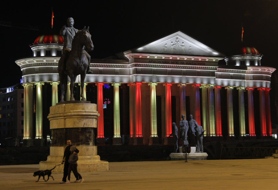 In this Oct. 23, 2012 photo people walk by the statue of well-known revolutionary figure Goce Delcev, left and "Boatmen of Thessaloníki" monument, right, in front of the newly-built Museum of Archaeology in downtown Skopje, Macedonia. Grandiose buildings, monuments, fountains and bridges are dotting the city center as part of a government project called Skopje 2014, officially intended to rebuild a city that lost many of its landmarks in a 1963 earthquake. (AP Photo/Darko Vojinovic)