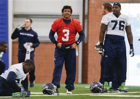 Seattle Seahawks quarterback Russell Wilson smiles during stretches while teammate Russell Okung (R) looks on at their NFL Super Bowl XLVIII football practice in East Rutherford, New Jersey, January 30, 2014. REUTERS/Shannon Stapleton
