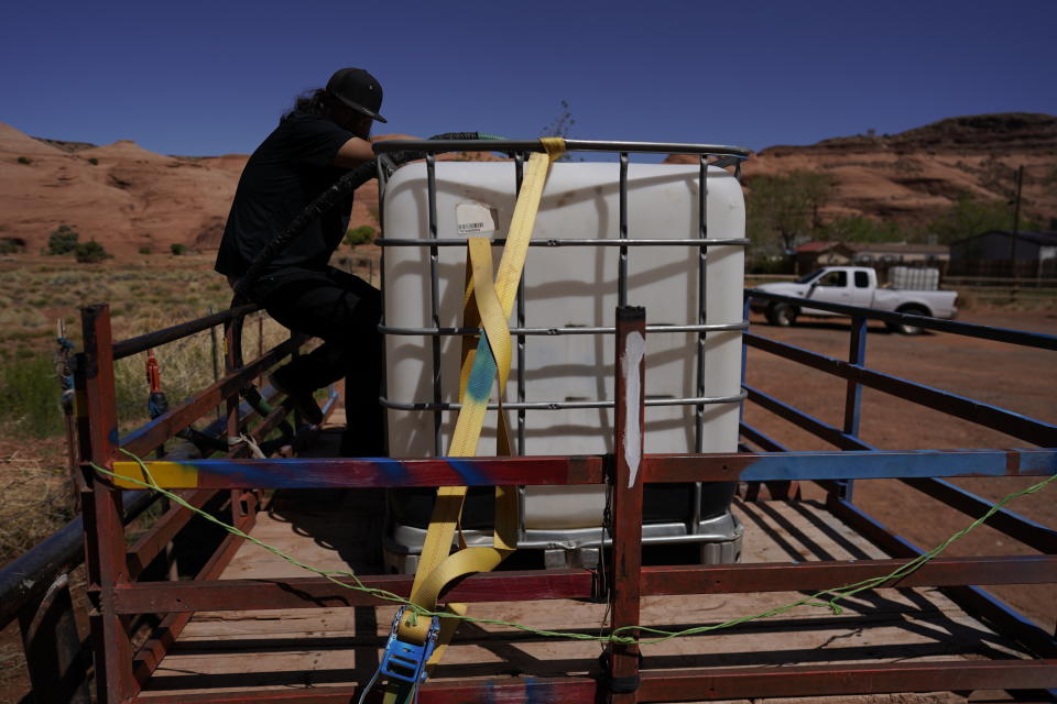 In this April 27, 2020, photo, Chris Topher Chee waits for water to fill a tank in the back of his truck to haul home in Oljato-Monument Valley, Utah, on the Navajo reservation. Even before the pandemic, people living in rural communities and on reservations were among the toughest groups to count in the 2020 census. (AP Photo/Carolyn Kaster)