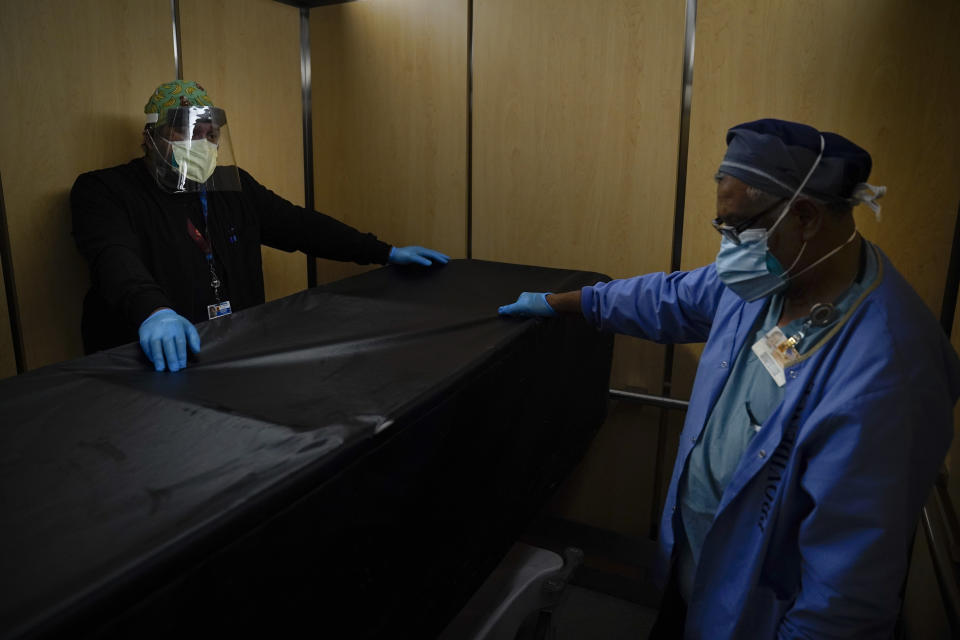 FILE - In this Jan. 9, 2021, file photo, transporters Miguel Lopez, right, Noe Meza move a body of a COVID-19 patient to a morgue at Providence Holy Cross Medical Center in the Mission Hills section of Los Angeles. The U.S. death toll from COVID-19 has topped 500,000 — a number so staggering that a top health researchers says it is hard to imagine an American who hasn't lost a relative or doesn't know someone who died. (AP Photo/Jae C. Hong, File)