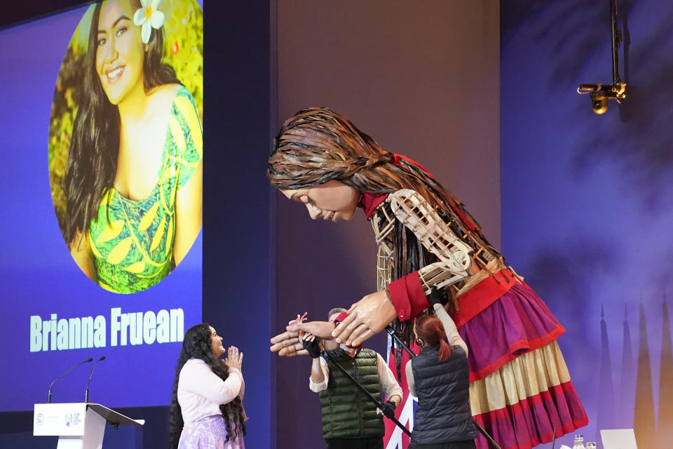 Brianna Fruean, an activist and environmental advocate for Samoa, greets the giant puppet Little Amal inside the venue of the COP26 U.N. Climate Summit in Glasgow, Scotland, Tuesday, Nov. 9, 2021. The U.N. climate summit in Glasgow has entered it's second week as leaders from around the world, are gathering in Scotland's biggest city, to lay out their vision for addressing the common challenge of global warming. (AP Photo/Alberto Pezzali)