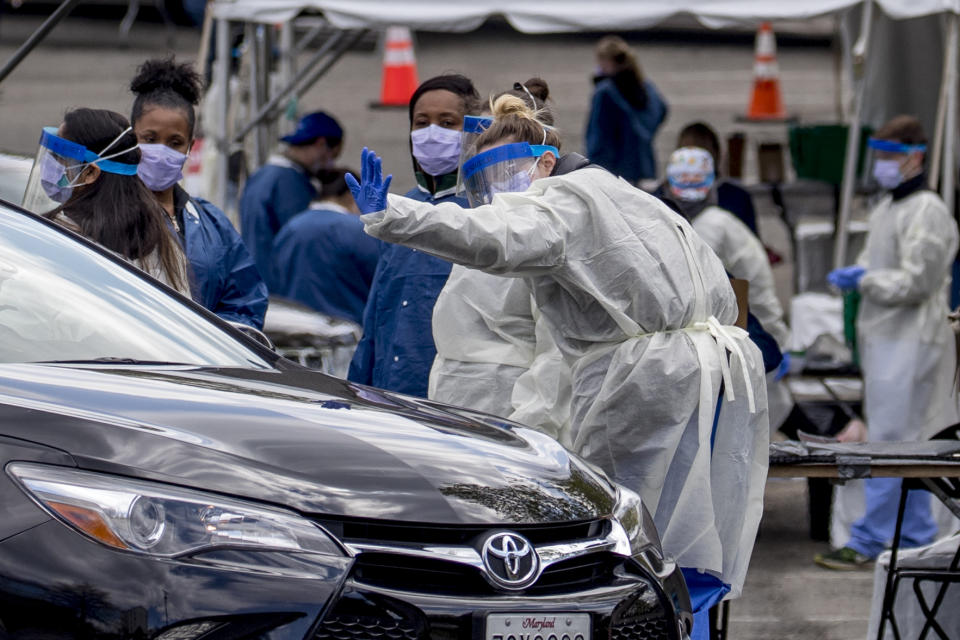 A medical worker waves goodbye after testing a young person for COVID-19 at a Children's National Hospital drive-through (drive-in) coronavirus testing site at Trinity University, Thursday, April 16, 2020, in Washington. (AP Photo/Andrew Harnik)