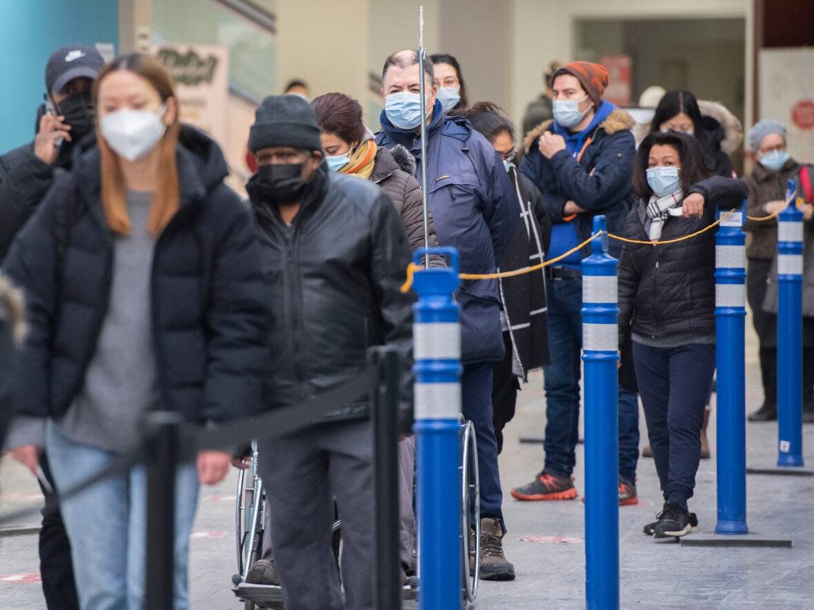 People wait in line at a COVID-19 vaccination site in Montreal, Sunday, January 16, 2022. Saskatchewan is looking at a 40 per cent test positivity rate on Monday, which is based only on those eligible for a PCR test and doesn't include positive rapid test results. (Graham Hughes/The Canadian Press - image credit)