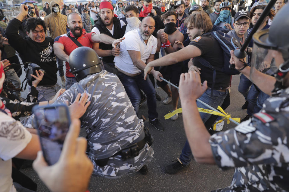 Anti-government protesters clash with riot police on a road leading to the parliament building in downtown Beirut, Lebanon, Tuesday, Nov. 19, 2019. Scuffles have broken out in central Beirut as hundreds of anti-government protesters tried to prevent lawmakers from reaching Parliament. (AP Photo/Hassan Ammar)