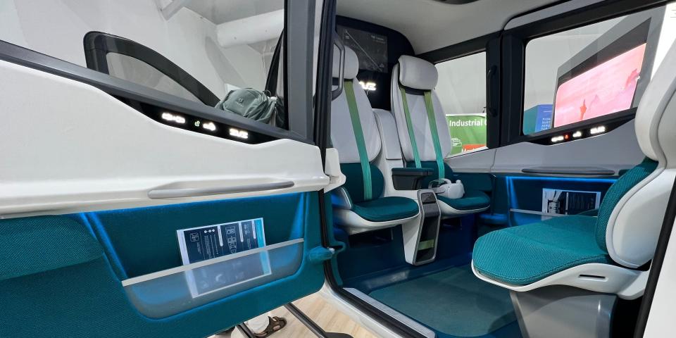 An Eve Air Mobility cabin model has four seats in facing pairs, with teal cushions.