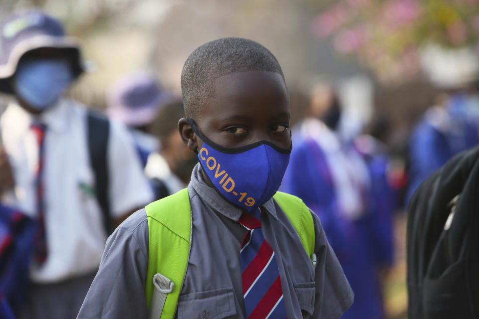 A child wearing a mask queues outside school in Harare, Zimbabwe, Monday, Sept, 28, 2020. Zimbabwe schools have reopened in phases, but with smaller number of pupils,more teachers and other related measures to enable children to resume their education without the risk of a spike in COVID-19 infections. (AP Photo/Tsvangirayi Mukwazhi)