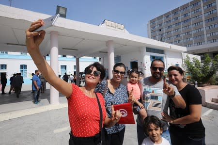 People pose for a picture after casting their vote during presidential election in Tunis