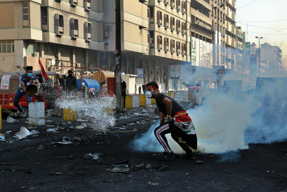 An anti-government protester throws water as another prepares to throw back a tear gas canister fired by police, during ongoing protests in Baghdad, Iraq, Wednesday, Nov. 13, 2019. Protesters say an intensifying crackdown by Iraqi authorities is instilling fears but remain defiant with calls for millions to return to the streets this week. (AP Photo/Hadi Mizban)