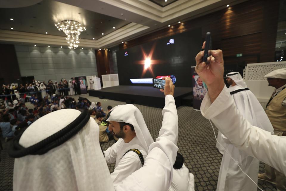 People watch a live broadcast of a Russian Soyuz MS-15 space mission, that took off from the Baikonur Cosmodrome in Kazakhstan, carrying Emirati Astronaut Hazzaa al-Mansoori and two other astronauts heading to the International Space Station, in Abu Dhabi, United Arab Emirates, Wednesday, Sept. 25, 2019. (AP Photo/Kamran Jebreili)