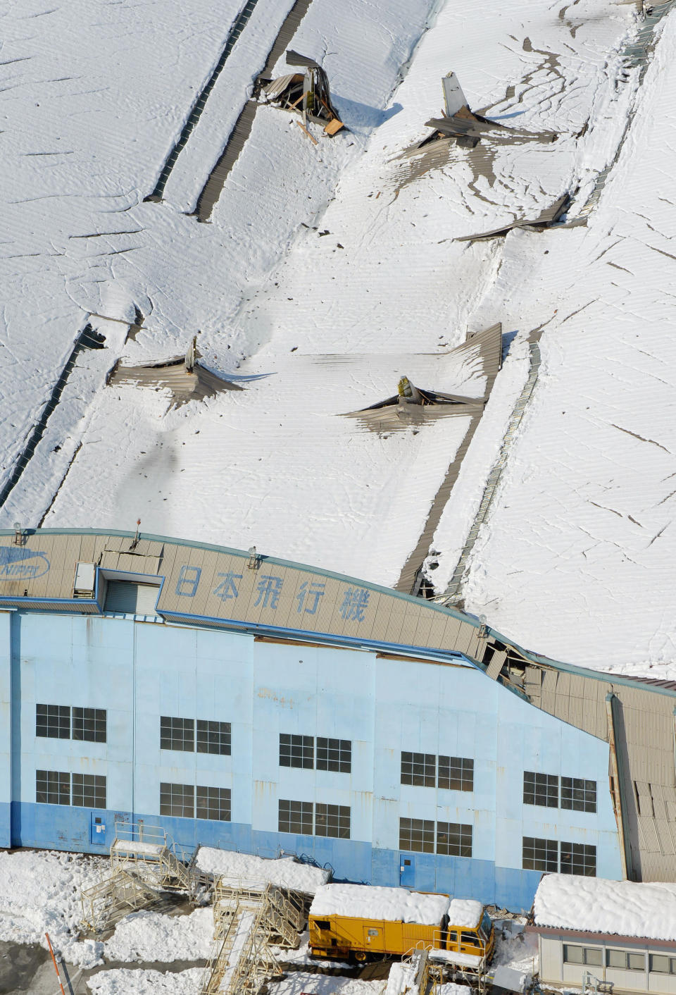 The vertical tail, top right, of a plane sticks out of the sagging roof of a hangar after heavy snowfall at Nippi Corp.'s aircraft maintenance and repair division in Yamamo, near Tokyo, Sunday, Feb. 14, 2014. The second heavy snowfall this month has hit eastern Japan, killing more than 10 people and injuring hundreds, while paralyzing traffic and causing power outages. Japan's weather agency said Sunday that the low pressure system was traveling north, dumping more snow to the area after passing the Tokyo region. (AP Photo/Kyodo News) JAPAN OUT, CREDIT MANDATORY