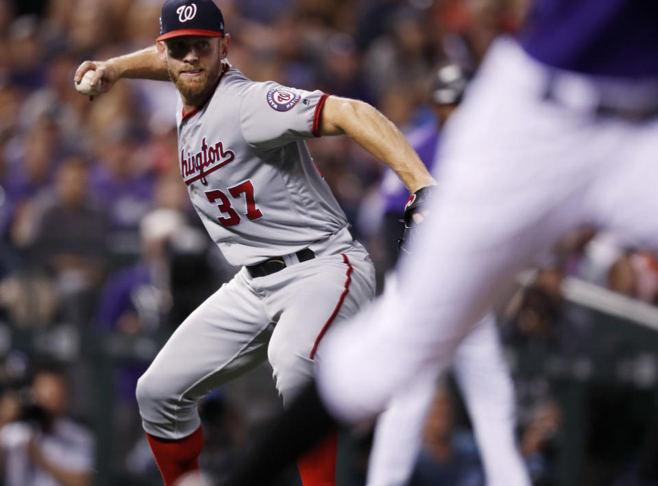 Washington Nationals starting pitcher Stephen Strasburg, back throws to first base to put out Colorado Rockies pinch-hitter Raimel Tapia in the second inning of a baseball game Saturday, Sept. 29, 2018, in Denver. (AP Photo/David Zalubowski)