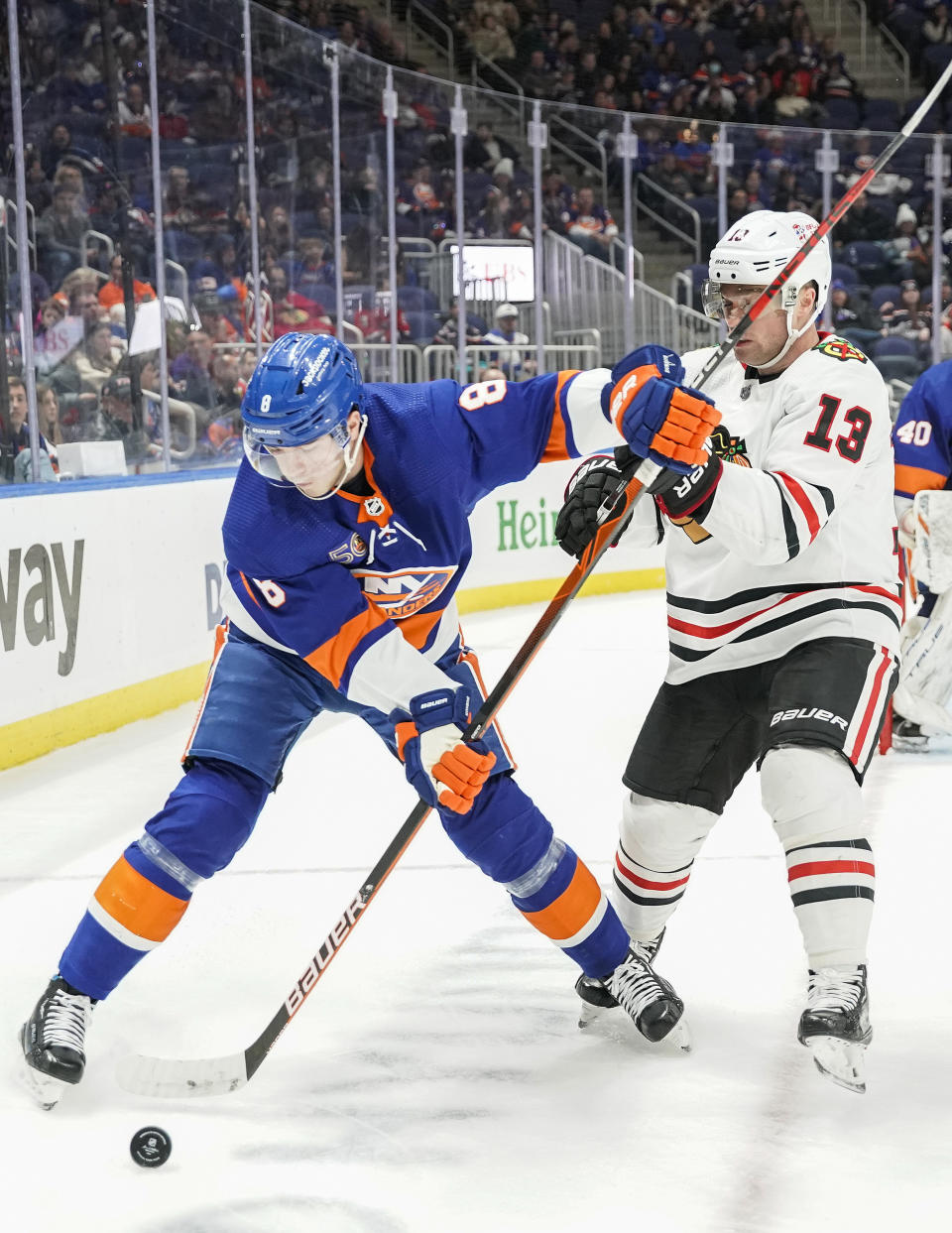 New York Islanders defenseman Noah Dobson (8) and Chicago Blackhawks center Max Domi (13) fight for the puck during the third period of an NHL hockey game on Sunday, Dec. 4, 2022, in Elmont, N.Y. (AP Photo/Eduardo Munoz Alvarez)