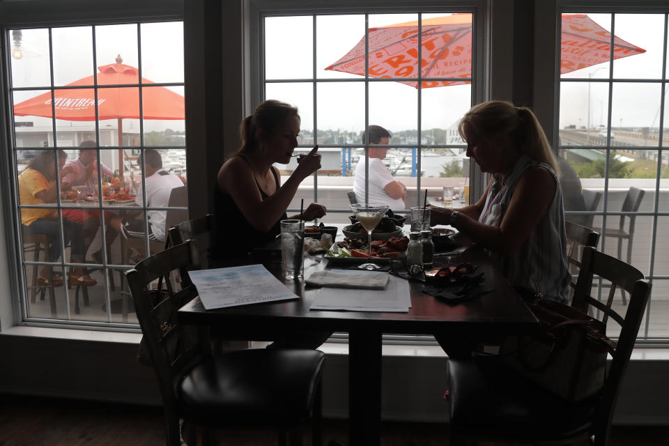 FILE- In this June 22, 2020, file photo two women eat lunch indoors at Portside Restaurant in Salisbury, Mass., after COVID-19 state guidelines allowed for indoor dining. A new poll from The Associated Press-NORC Center for Public Affairs Research shows Americans becoming less concerned about infection and less supportive of restrictions. But with experts warning that hospitals in some states in the South and West will soon be inundated, the poll finds many Americans have not embraced reopening even as state and local officials have. (AP Photo/Elise Amendola, File)