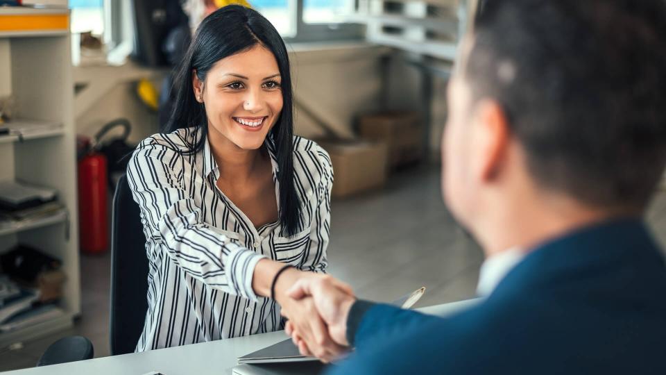 Woman car dealer shaking hands with client.