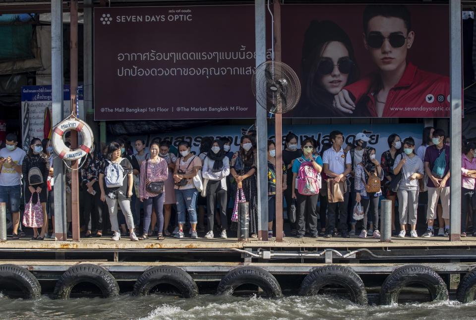 Boat passengers on a jetty wear face masks in Bangkok, Thailand, Tuesday, Jan. 28, 2020, to protect themselves from new virus infection. Panic and pollution drive the market for protective face masks, so business is booming in Asia, where fear of the coronavirus from China is straining supplies and helping make mask-wearing the new normal. (AP Photo/Gemunu Amarasinghe)