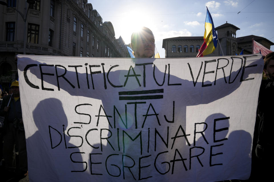 A man holds a banner that reads "Green certificate = Blackmail, Discrimination, Segregation" as he takes part in an anti-government protest organised by the far-right Alliance for the Unity of Romanians or AUR, in Bucharest, Romania, Saturday, Oct. 2, 2021. Thousands took to the streets calling for the government's resignation, as Romania reported 12,590 new COVID-19 infections in the past 24 hour interval, the highest ever daily number since the start of the pandemic. (AP Photo/Vadim Ghirda)