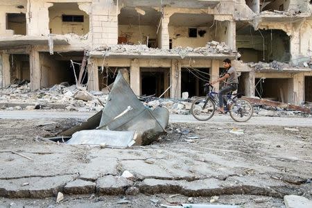 A man rides a bicycle near damaged ground in the rebel held besieged al-Sukkari neighbourhood of Aleppo, Syria October 19, 2016. REUTERS/Abdalrhman Ismail