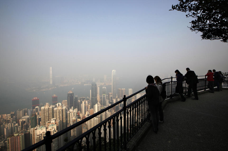 In this Jan. 11, 2013 photo, visitors get a bird's-eye view of the upscale homes nestled amid the lush green flanks of the mountain and the city's skyscrapers beyond on the Lugard road, a trail on the Victoria Peak in Hong Kong. Hong Kong's hyper-urban highlights might not be everyone's cup of tea. But one of the city's best kept secrets is how easy it is to get away from the crowds. There are numerous country parks with hiking trails, many of them offering scenic panoramas. (AP Photo/Kin Cheung)