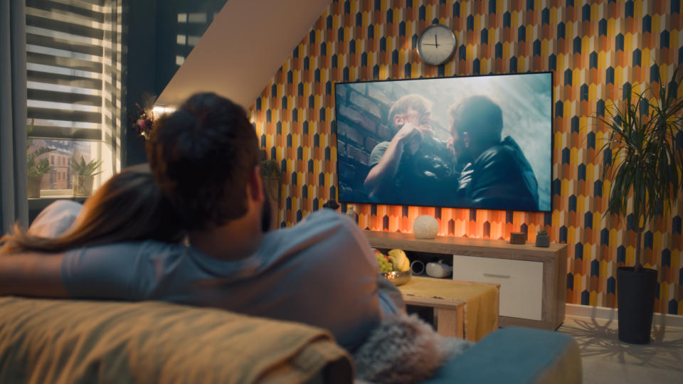 Two people cuddling while watching TV in a cozy living room setting