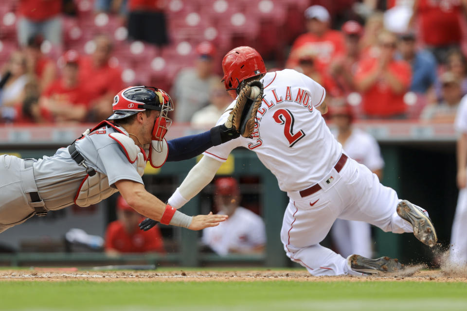 Cincinnati Reds' Nick Castellanos, right, scores a run ahead of the tag from St. Louis Cardinals' Andrew Knizner, left, during the third inning of the first baseball game of a doubleheader in Cincinnati, Wednesday, Sept. 1, 2021. (AP Photo/Aaron Doster)