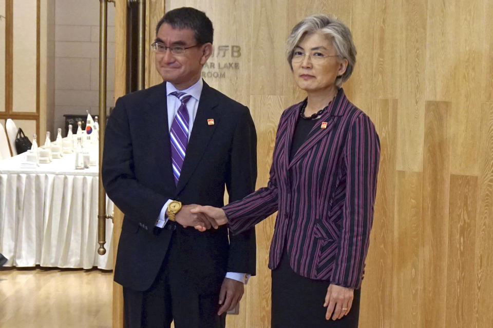 South Korea's Foreign Minister Kang Kyung-wha, right, shakes hands with Japan's Foreign Minister Taro Kono, left, ahead of their meeting in Beijing, China, Wednesday, Aug. 21, 2019. (Korea Pool/Yonhap via AP)