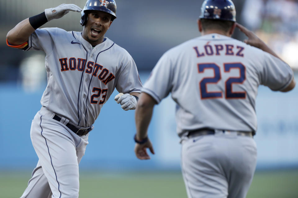 Houston Astros' Michael Brantley, left, celebrates with third base coach Omar Lopez while rounding the bases after hitting a solo home run against the Los Angeles Dodgers during the first inning of a baseball game in Los Angeles, Wednesday, Aug. 4, 2021. (AP Photo/Alex Gallardo)