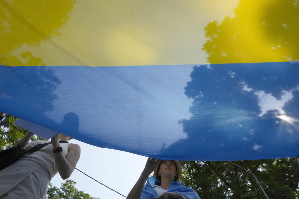 Ukrainian people living in Thailand hold Ukraine national flag during a rally to mark the one-year anniversary of Russia's invasion of Ukraine, in Bangkok, Thailand, Friday, Feb. 24, 2023. (AP Photo/Salkchai Lalit)