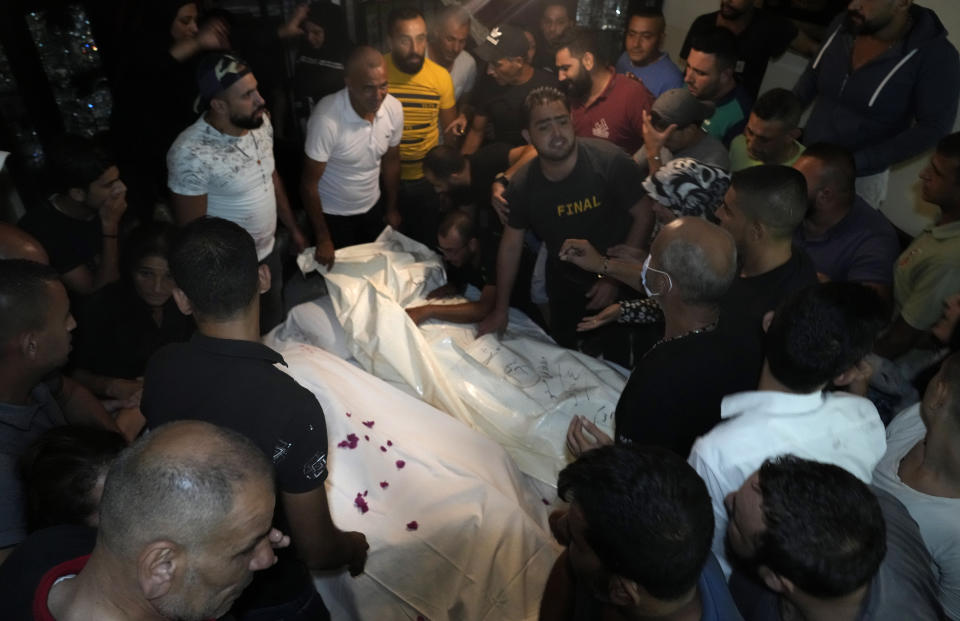 Mourners gather around two of several victims who were on a boat carrying migrants from Lebanon that sank in Syrian waters, after they bring back home their dead bodies, in Tripoli, north Lebanon, Sept. 23, 2022. Syria's health minister says several people have been killed from a boat that sank migrants from Lebanon off Syria's coast. The incident is the deadliest since a surging number of Lebanese, Syrians, and Palestinians have tried to flee crisis-hit Lebanon by sea to Europe. (AP Photo/Bilal Hussein)