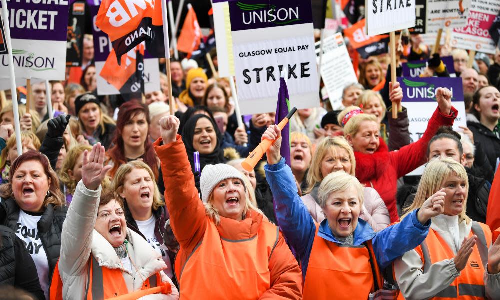 People hold placards during a rally for equal pay for Glasgow council workers.