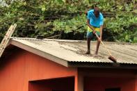 Local residents clear ash from a roof after a series of eruptions from La Soufriere volcano