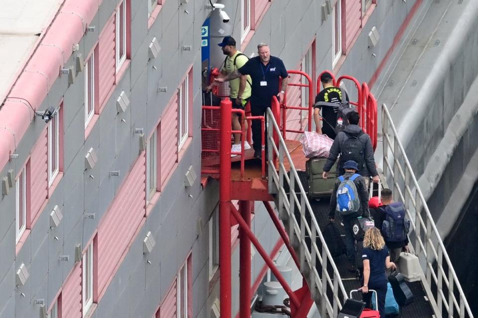 People carrying bags are seen walking up the gang-way into the Bibby Stockholm accommodation barge, moored to the quayside at Portland Port in Portland, on the south-west coast of England on August 7 (AFP via Getty Images)