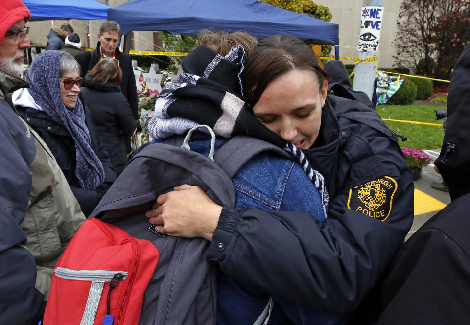 In this Saturday, Nov. 3, 2018, photo Pittsburgh Police officer Sarah Pratt gets a hug from before a Shabbat morning worship service led by Rabbi Chuck Diamond is held outside the Tree of Life Synagogue in Pittsburgh. Synagogues, mosques, churches and other houses of worship are routinely at risk of attack in many parts of the world. And so worshippers themselves often feel the need for visible, tangible protection even as they seek the divine. (AP Photo/Gene J. Puskar)