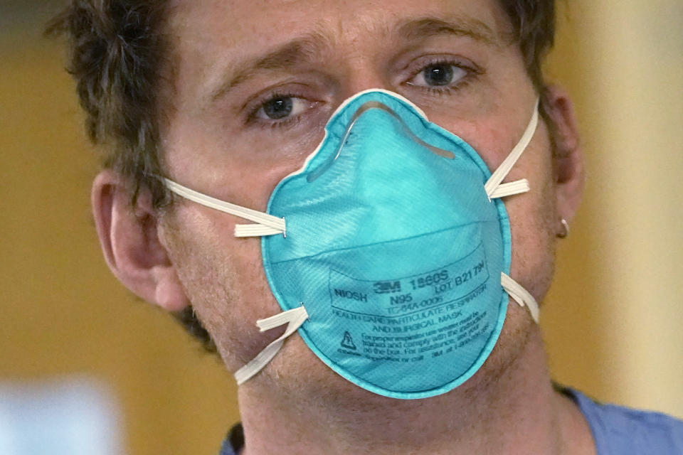 FILE - Registered nurse Scott McGieson wears an N95 mask as he walks out of a patient's room in the acute care unit of Harborview Medical Center, Jan. 14, 2022, in Seattle. The Biden administration will begin making 400 million N95 masks available for free to Americans starting next week, now that federal officials are emphasizing their better protection against the omicron variant of COVID-19 over cloth face coverings. The White House announced Wednesday that the masks will come from the government's Strategic National Stockpile, which has more than 750 million of the highly protective masks on hand. . (AP Photo/Elaine Thompson, File)