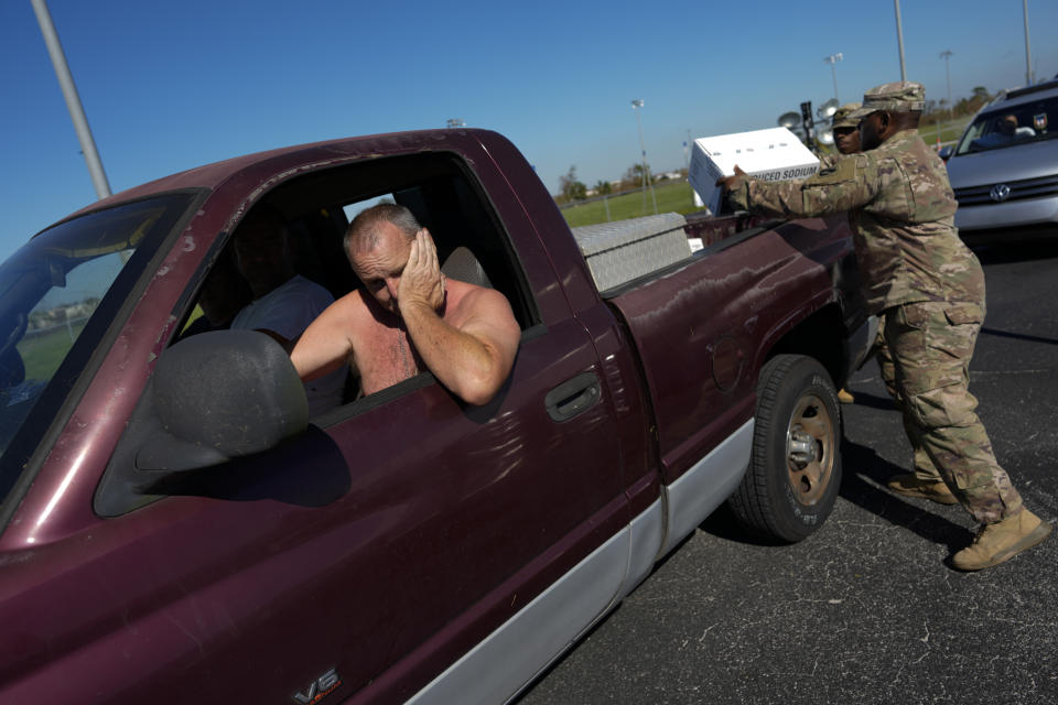 Members of the US Army National Guard load supplies into the back of a pick-up at a drive-through distribution point handing out food, water, and ice to local residents in need, three days after the passage of Hurricane Ian, in Fort Myers, Fla., Saturday, Oct. 1, 2022. (AP Photo/Rebecca Blackwell)